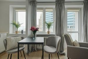 a living room with a table and chairs and windows at Urban Oasis Private Apartment with Palace of Culture View in Warsaw