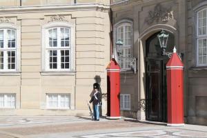 Una donna in piedi di fronte a un edificio con colonne rosse di ApartmentInCopenhagen Apartment 1484 a Copenaghen