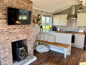 a kitchen with a brick fireplace with a bench and a television at Brackenrigg Lodge in Felton