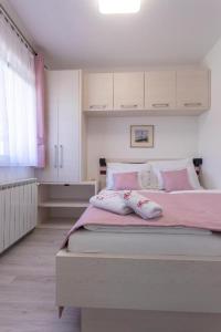 a bedroom with a pink bed with pillows on it at Villa Beganović in Krk