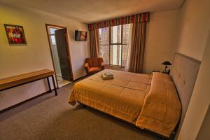 a bedroom with a bed and a chair and a window at Pan American Hotel in La Paz