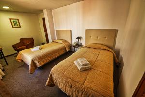 a hotel room with two beds and a chair at Pan American Hotel in La Paz