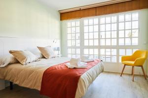 1 dormitorio con 1 cama con silla y ventana en Padrón Suites, en Padrón