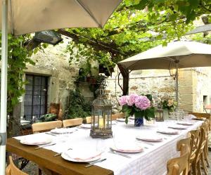 a long table with plates and flowers and an umbrella at Luxury stay in 250 year old wine farm house and gardens in Rüschlikon