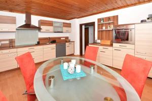 cocina grande con mesa de cristal y sillas rojas en Ferienwohnung Karawankenblick, en Bach