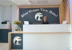 Diaz Ocean View Hotel في خليج موسيل: امرأة تقف وراء مكتب في فندق مطل على المحيط بالأسماك