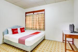 een slaapkamer met een bed, een bureau en een raam bij OYO 92505 Asta Guesthouse in Yogyakarta