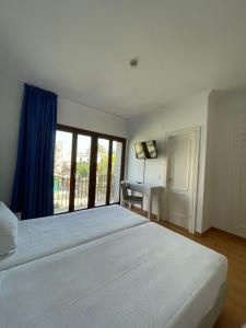 a bedroom with a large white bed and a desk at Hotel Trafalgar in Jerez de la Frontera