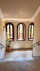 una habitación vacía con cuatro ventanas y una maceta en The Red House, en Marrakech
