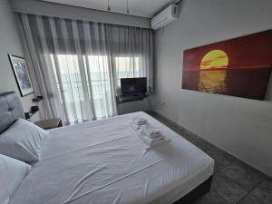 a bedroom with a white bed and a television at Studio Just On The Beach in Paralia Katerinis