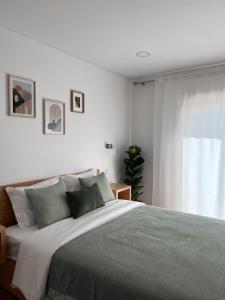 a white bedroom with a large bed and a window at Jasmine Hotel in São Pedro de Alva