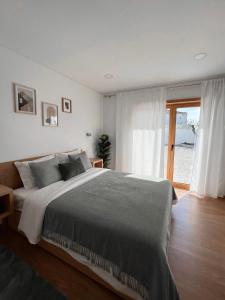 a bedroom with a large bed and a large window at Jasmine Hotel in São Pedro de Alva