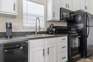 a kitchen with white cabinets and a black refrigerator at Sun Outdoors New Orleans North Shore in Robert