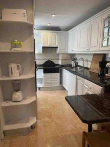 a kitchen with white cabinets and a black counter top at Bright flat with view to the Castle and the Museum in Alicante