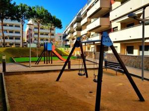 um parque infantil vazio com um baloiço numa cidade em Maravilloso piso con piscina a 200m de la playa em Lloret de Mar
