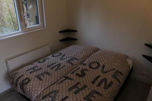 un pequeño dormitorio con una cama con una manta. en Chalet Fietsplezier B19, en Renswoude