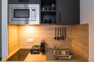 una cucina con lavandino e forno a microonde di Apartments an der Kö a Dusseldorf