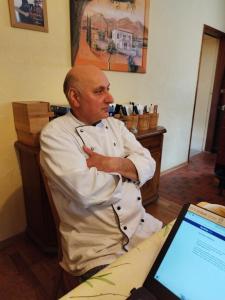 a chef sitting in front of a laptop computer at Pizzeria Brar in Haina