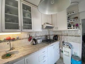 eine Küche mit weißen Schränken und einem Waschbecken in der Unterkunft Cheerful Bodrum Home in Bodrum City