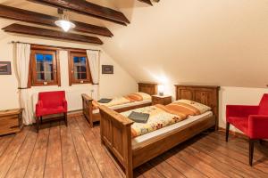 um quarto com 2 camas e 2 cadeiras vermelhas em Pivovar BUC Kvačany em Kvačany