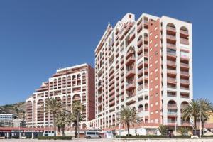 a large building with palm trees in front of it at Ferrobus Duplex in Cullera