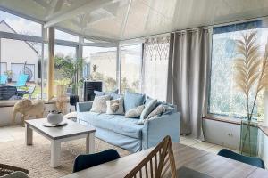 uma sala de estar com um sofá azul e uma mesa em FM42 - À Ciel Ouvert Maison avec grande veranda et jardin em Friaucourt
