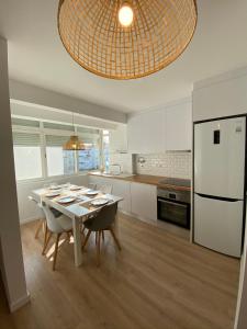 Carcavelos Beach walking distance room in shared apartment في أويراس: مطبخ مع طاولة مع كراسي وثلاجة بيضاء
