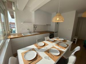 Carcavelos Beach walking distance room in shared apartment في أويراس: مطبخ مع طاولة عليها صحون بيضاء