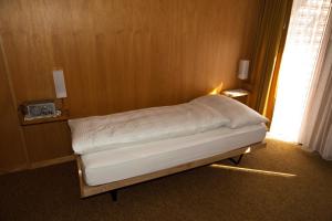 ein kleines Bett in einem Zimmer mit Fenster in der Unterkunft Hotel Garni Simplon in Brigerbad
