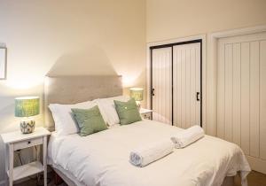 a bedroom with a large white bed with green pillows at The Kennels in Ballogie