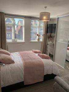 a bedroom with a bed with pink pillows and windows at Kensington Luxury Apartment on Gated Development in Leafy edge of Chorley Town Centre in Chorley