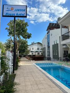 a sign for a house hotel next to a swimming pool at London House Hotel in Kemer