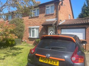 a car parked in front of a house with a dog in the doorway at Comfy Letchworth Apartment by Leecroft Stays in Letchworth