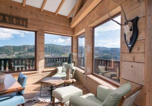 um quarto com cadeiras e janelas num chalé de madeira em Luxueux chalet avec vue sur les pistes et le Hohneck em Le Tholy