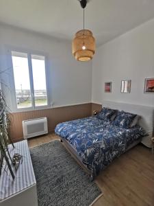 um quarto com uma cama com um edredão azul e 2 janelas em SPACIEUX APPARTEMENT FRONT DE MER em Saintes-Maries-de-la-Mer