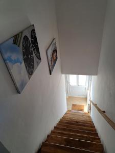 een trap met een klok en foto's aan de muur bij Apartman BLOOM in Petrovaradin