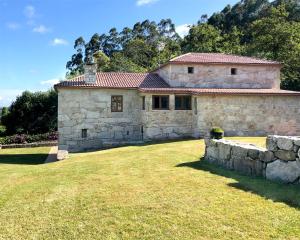 a large stone house with a grass yard at Casa Valdamor in Meaño