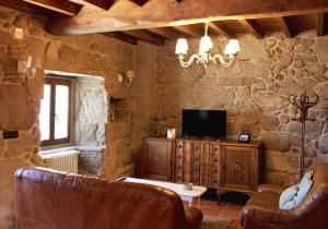 a living room with a tv and a stone wall at Casa Valdamor in Meaño