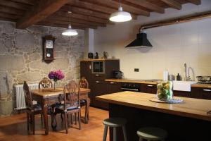 a kitchen with a wooden table and chairs and a counter at Casa Valdamor in Meaño