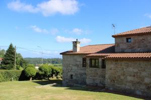 a stone house with a grassy yard in front of it at Casa Valdamor in Meaño
