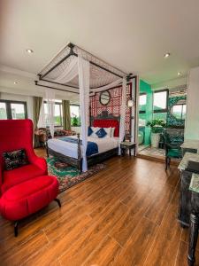ein Schlafzimmer mit einem Himmelbett und einem roten Stuhl in der Unterkunft Athena Hotel Quy Nhơn in Quy Nhon
