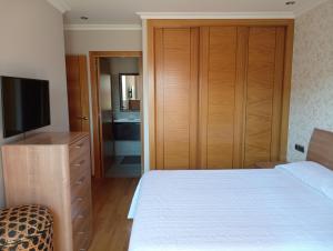 a bedroom with a bed and a dresser with a television at A Devesa in Redondela