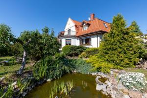 a house with a pond in front of it at Dworek Zielińskich-Domki, Apartamenty, Podgrzewany basen, Parking in Rewal