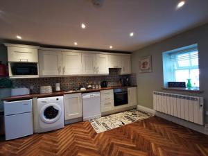 uma cozinha com electrodomésticos brancos e piso em madeira em Knockreagh Farm Cottages, Callan, Kilkenny em Kilkenny