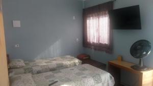 une chambre avec deux lits, un ventilateur et une fenêtre dans l'établissement Casa familiar quarto, cozinha, banheiro e piscina a praia está a 700 metros, à Peruíbe