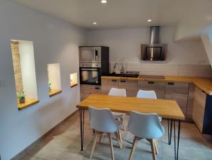 a kitchen with a wooden table and white chairs at Le Green Duplex moderne en hypercentre in Sarreguemines