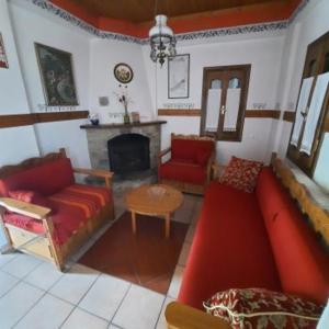 a living room with a red couch and a fireplace at Milea Byron House Tsagarada in Tsagarada