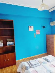 um quarto com uma parede azul e uma cama em Central Kiato em Kiato