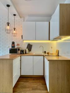 una cocina con armarios blancos y encimeras de madera en REMAR - Apartamentai prie Necko Ežero, en Augustów