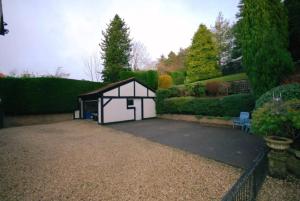 ein kleiner weißer Schuppen im Garten in der Unterkunft Edwardian Manor near Glasgow City with HEATED POOL & HOT TUB in Giffnock